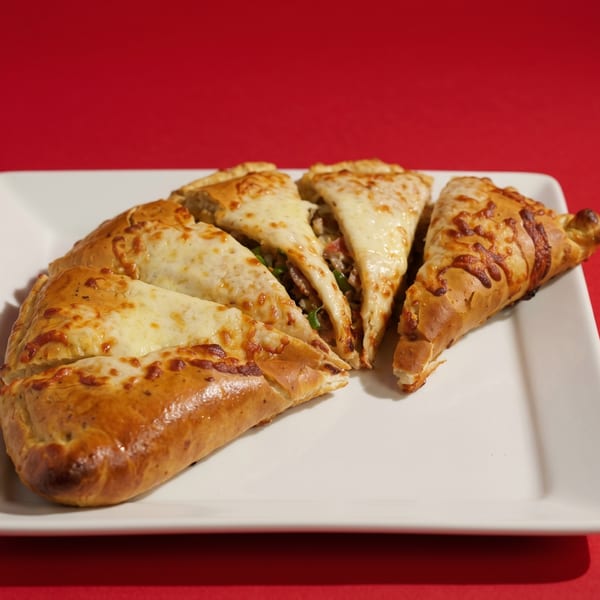 Four triangular slices of cheesy calzone, revealing meat and vegetables inside, on a white plate.