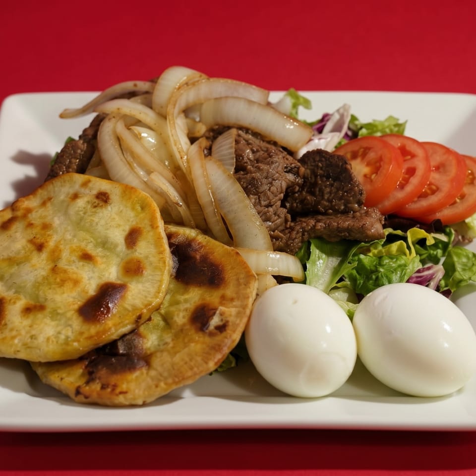 A plate of steak with sautéed onions, two flatbreads, a side salad, and two hard-boiled eggs.